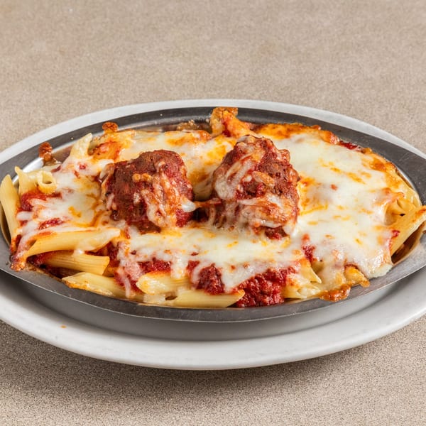Baked penne pasta with meatballs, marinara sauce, and melted mozzarella cheese in a metal dish.