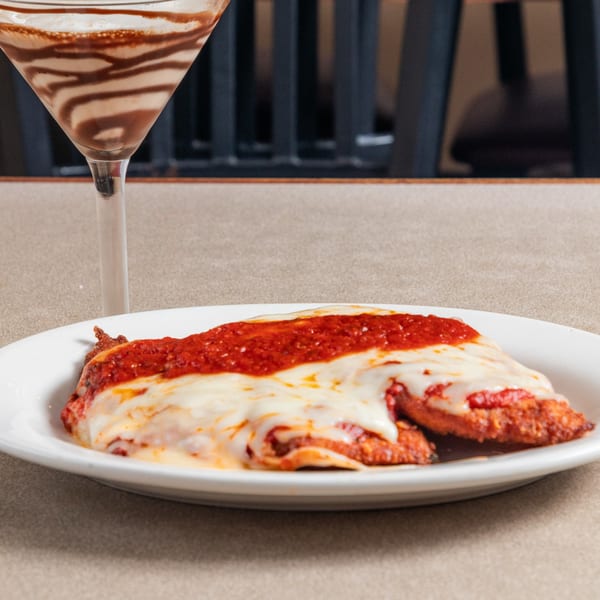 Chicken Parmesan with melted mozzarella and red sauce, next to a chocolate martini.